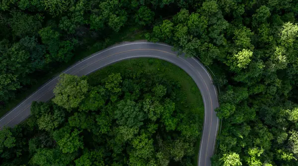 stock image Aerial view asphalt road on green forest, Curve asphalt road on mountain green forest, Countryside road passing green forrest and mountain.