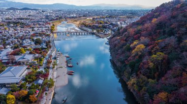 Kyoto, Japonya, Arashiyama nehri boyunca sonbahar mevsiminde, Arashiyama nehri boyunca, Arashiyama nehri boyunca, Arashiyama, Japonya, Asya 'da, Arashiyama, Kyoto, Japonya, Togetsu ya da Togetsukyo köprüsü antik mimari ve tekneler bulunmaktadır..