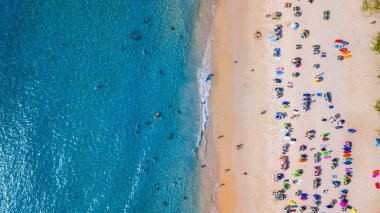 Hava manzaralı insanlar kumlu sahil ve mavi deniz suyunda tatil, Sandy plajı renkli şemsiyeli turistler yüzüyor, tropikal deniz manzaralı turkuaz su seyahati ve tatil.