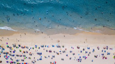 Hava manzaralı insanlar kumlu sahil ve mavi deniz suyunda tatil, Sandy plajı renkli şemsiyeli turistler yüzüyor, tropikal deniz manzaralı turkuaz su seyahati ve tatil.