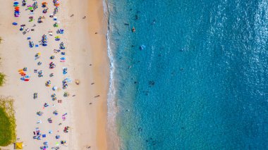 Hava manzaralı insanlar kumlu sahil ve mavi deniz suyunda tatil, Sandy plajı renkli şemsiyeli turistler yüzüyor, tropikal deniz manzaralı turkuaz su seyahati ve tatil.