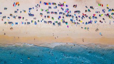 Hava manzaralı insanlar kumlu sahil ve mavi deniz suyunda tatil, Sandy plajı renkli şemsiyeli turistler yüzüyor, tropikal deniz manzaralı turkuaz su seyahati ve tatil.