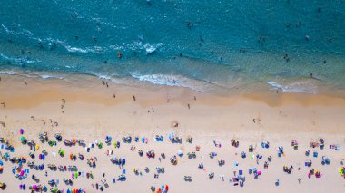 Hava manzaralı insanlar kumlu sahil ve mavi deniz suyunda tatil, Sandy plajı renkli şemsiyeli turistler yüzüyor, tropikal deniz manzaralı turkuaz su seyahati ve tatil.