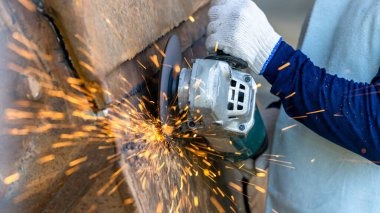 Elektrikli öğütücüyle metal işleme, metal işçiliğinde kıvılcımlar, fabrikadaki çelik yapıda elektrik tekerleği öğütme. Öğütücü tekerlekten kıvılcımlar, endüstriyel atölyedeki elektrikli öğütücü.