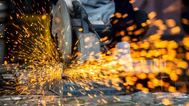 Elektrikli öğütücüyle metal işleme, metal işçiliğinde kıvılcımlar, fabrikadaki çelik yapıda elektrik tekerleği öğütme. Öğütücü tekerlekten kıvılcımlar, endüstriyel atölyedeki elektrikli öğütücü.