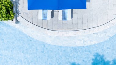 Yazın yüzme havuzu mavi su, şemsiye havuzu ve plaj sandalyesi tatil tatili için tatil otelinde güneşli yüzme havuzu ve şemsiye havuzu, yaz tatili konsepti..