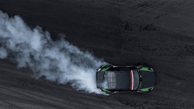 Motorsporu araba asfalt yarış pistinde sürükleniyor. Yanan tekerlek lastikleri dumanı, drift motor sporu araba sürüklenme yarışı, asfalt yarış pistinde profesyonel sürüş arabası, araba hareketi bulanık..