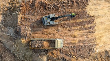 Kazı kazıları toprağı inşaat sahasında taşır, Kazı ve inşaat sahasında kazı yapar, Crawler kazıcı kazıcıları inşaat alanındaki taşımacılık kamyonunda toprak çakılları, Top view.