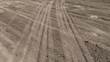 Toprak kumdaki lastik izi ya da yol kenarındaki çamur, lastik izi araç tekerleği şekli, toprak dokusu, kuru çamur arkaplan ve desen üzerindeki üst manzara lastikleri..
