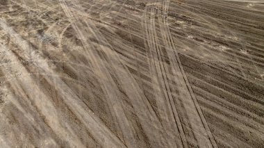 Toprak kumdaki lastik izi ya da yol kenarındaki çamur, lastik izi araç tekerleği şekli, toprak dokusu, kuru çamur arkaplan ve desen üzerindeki üst manzara lastikleri..