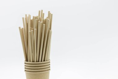 Beyaz arka planda kağıt bardaklar ve kağıt pipetler, açık havada içmek için aksesuarlar, ekoloji çevre dostu geri dönüşüm, çevre dostu yeniden kullanılabilir kağıt pipetler, kahve veya çay içmek için Kraft kağıdı pipetleri.