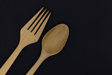 Ahşap kaşık ve çatal siyah arka planda, bir tahta kaşık ve çatal mutfak takımı, çevre dostu ahşap çatal ve kaşık, Top View