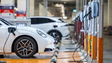 EV şarj istasyonu ve elektrikli araba şarj istasyonu EV pili şarj istasyonu, elektrikli motoru olan araç prizi, EV şarjı temiz enerji, araba parkındaki şarj noktası.