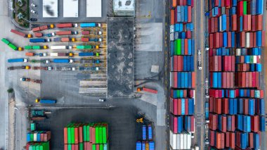 Hava görüntüsü tırları otoparkta duruyor ve konteynır terminali terminalinde yükleme ve boşaltma için bekliyor. Küresel lojistik ulaşım tırları..