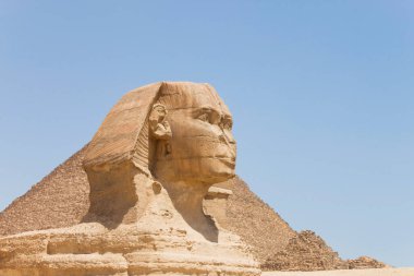 Piramitlere ve mavi gökyüzüne karşı Büyük Sfenks, Giza, Mısır