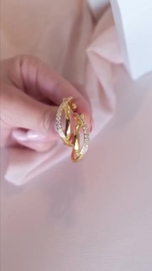 Kadının eli pembe arka planda Hoop küpelerini tutuyor. Dikey video.