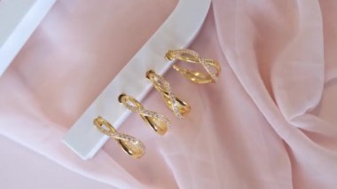 Hoop küpeler beyaz tezgahta katlanmış pembe kumaşın üzerinde oturuyor.