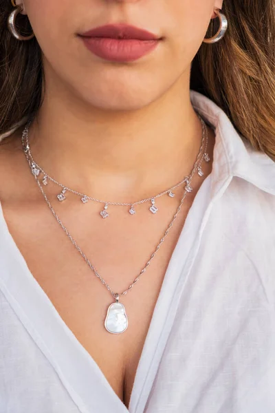 A beautiful young woman wearing silver clear and pearl necklaces and silver earrings. Beautiful valentine\'s gifts.