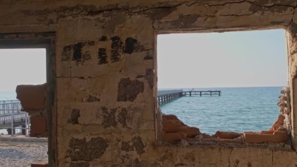 通过破败的房子里窗口是通过在 Argaka 塞浦路斯海滩码头视图 — 图库视频影像