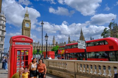 Londra, İngiltere - 19 Haziran 2023: Londra 'da Big Ben Saat Kulesi ve parlamentosu ile kırmızı geleneksel bir telefon kulübesinin önünde fotoğraf çeken turist ailesi.