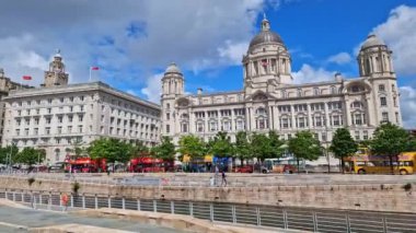 İnsanlar Liverpool rıhtımındaki Liverpool rıhtımında geziniyor ve The Three Graces ve diğer binalarda.