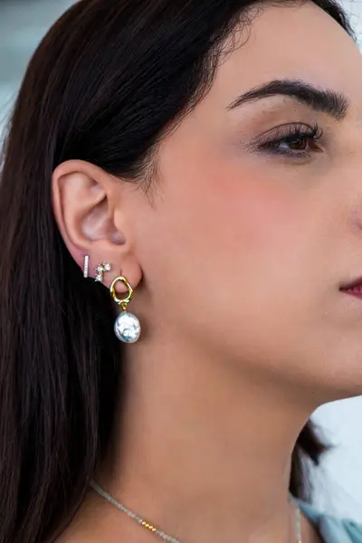stock image A beautiful young woman wearing pearl earrings and stud earrings with zirconia. Beautiful valentine's gifts.