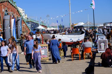 Brighton, İngiltere - 4 Mayıs 2024: İngiltere 'deki Brighton sahili boyunca yürüyen insanlar