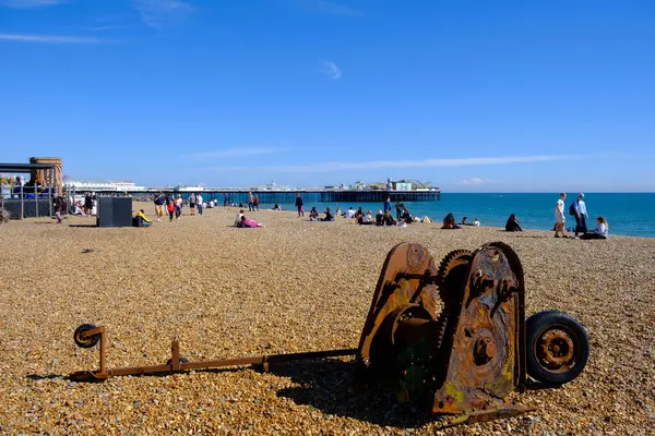 stock image Brighton, UK -  May 4, 2024: Brighton beachfront with old rusty equipment outside the Fishing Museum and the Palace Pier in the distance in England, United Kingdom