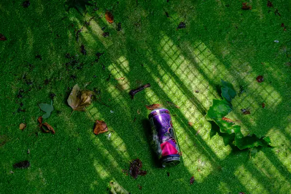 Durgun su yüzeyine düşen alüminyum enerji içeceği tenekesinin ve yapraklarının soyut bir şekilde ele geçirilmesi