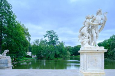 Beyaz mermer klasik heykeller, Lazienki Parkı 'ndaki yemyeşil verimli bir gölün yanında duruyor. Parkın aydınlanma dönemindeki sanatsal ve doğal ihtişamını yansıtıyor..