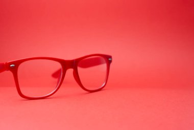 Kırmızı arka planda şeffaf lensli kırmızı gözlükler.