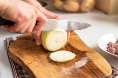 Bir adam keskin bir bıçakla tahtadan soğan kesiyor..