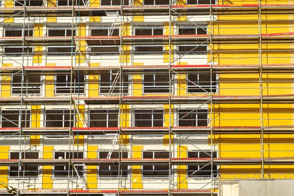 黄色の高層ビルの近くの赤い足場 複数階建ての建築 — ストック写真