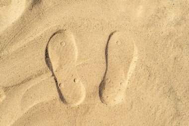 Sahildeki suyun yakınındaki kumda insan ayağının ayak izleri.