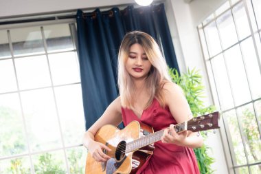 Akustik gitar çalan güzel bir Asyalı kadın. moda yaşam tarzı