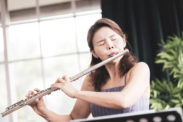 Flute classical instrument profestional player playing song.  A young and elegant Asian woman plays the flute. (Vintage Stye colour picture.)