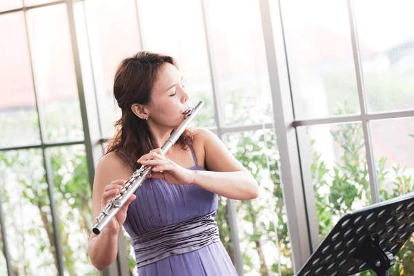 Flute classical instrument profestional player playing song.  A young and elegant Asian woman plays the flute. (Vintage Stye colour picture.)