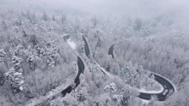 Romanya 'daki dağların ortasından geçen rüzgarlı ve eğimli bir yolun 4K' lık kış görüntüsü