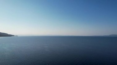 Yunanistan 'ın Sithonia kentindeki sembolik turkuaz ve safir Cennet plajlarının Atos Dağı manzaralı insansız hava aracı videosu. Yüksek kayalıklarla çevrili güzel bir kumsal manzarası.