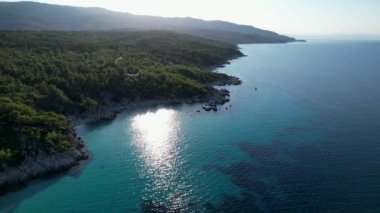 Yunanistan 'ın Sithonia kentindeki sembolik turkuaz ve safir Cennet plajlarının Atos Dağı manzaralı insansız hava aracı videosu. Yüksek kayalıklarla çevrili güzel bir kumsal manzarası.