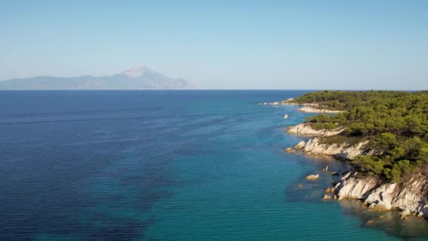 アトス山の景色を望むギリシャのシトニアの象徴的なターコイズとサファイアパラダイスビーチの空中ドローンビデオ 高い岩に囲まれた砂浜の美しい景色 — ストック動画