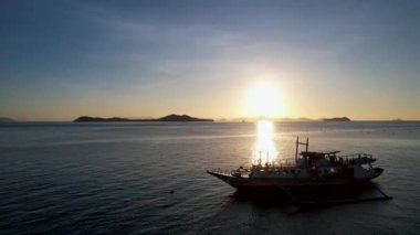 Filipinler 'in Linapacan şehrinde günbatımında geleneksel Filipinli tekne bangka. Turuncu gökyüzü günbatımı cennet kumsalı.