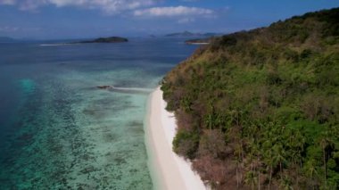 Filipinler, Palawan 'da beyaz kumlu ve kristal berrak suyu olan Cagdanao adasının 4K Hava Aracı videosu
