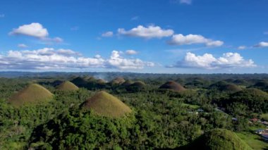 Filipinler 'in Bohol Adası' ndaki Chocolate Hills 'te doğanın güzelliği ile ilgili 4K hava aracı videosu. Bu isim, kurak mevsimde tepeleri kaplayan ve kahverengileşen çimlerden geliyor.
