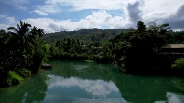 4K Zümrüt Loboc nehrinin nehir kenarındaki yolu ve Bohol, Filipinler 'deki evleri gösteren İHA videosu.