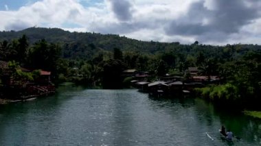 4K Zümrüt Loboc nehrinin nehir kenarındaki yolu ve Bohol, Filipinler 'deki evleri gösteren İHA videosu.