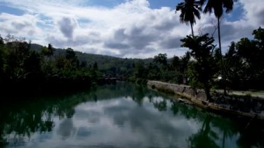 4K Zümrüt Loboc nehrinin nehir kenarındaki yolu ve Bohol, Filipinler 'deki evleri gösteren İHA videosu.
