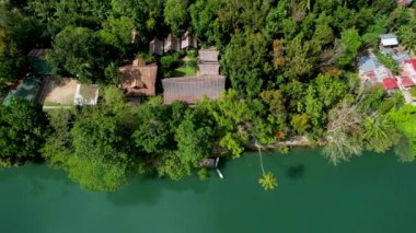 4K Zümrüt Loboc nehrinin nehir kenarındaki yolu ve Bohol, Filipinler 'deki evleri gösteren İHA videosu.