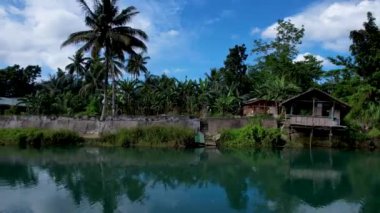 4K Zümrüt Loboc nehrinin nehir kenarındaki yolu ve Bohol, Filipinler 'deki evleri gösteren İHA videosu.