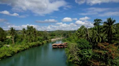 4K Zümrüt Loboc nehrinin nehir kenarındaki yolu ve Bohol, Filipinler 'deki evleri gösteren İHA videosu.